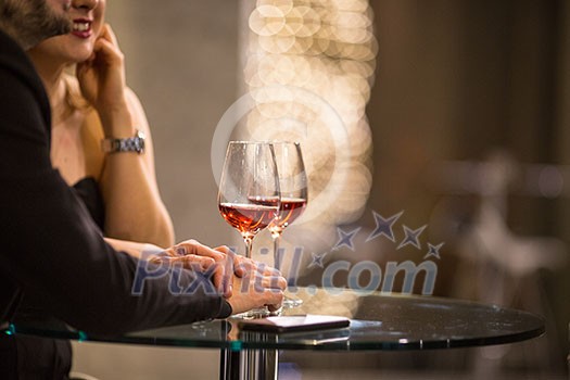 Man and a woman having drinks/glass of wine at a bar (shallow DOF; color toned image)