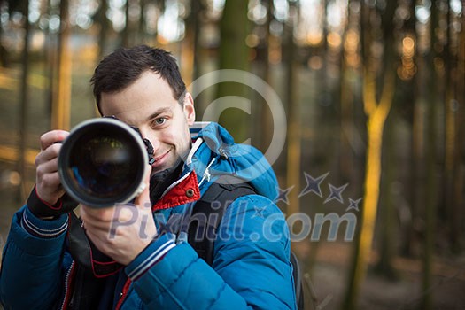 Young, male photographer taking photos with his huge, new, shiny, fast prime professional telephoto lens