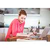 Woman in kitchen with laptop and a glass of wine, browsing the web, shopping online from her modern home (shallow DOF; color toned image)