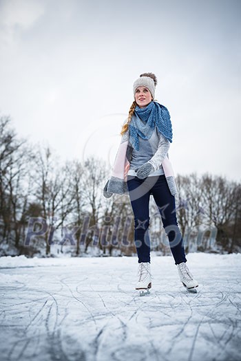 Young woman ice skating outdoors on a pond on a freezing winter day (color toned image; motion blurred image) Young woman ice skating outdoors on a pond on a freezing winter day (color toned image; motion blurred image)