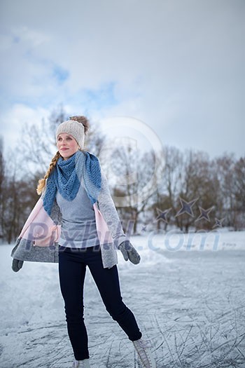 Young woman ice skating outdoors on a pond on a freezing winter day (color toned image; motion blurred image)