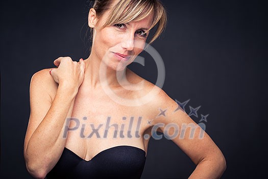 Portrait of a smiling middle aged caucasian woman against dark background - radiating confidence and feminity (shallow DOF; color toned image)