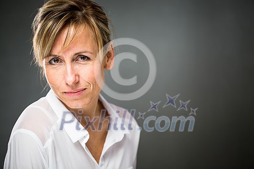 Portrait of a smiling middle aged caucasian woman against dark background - radiating confidence and feminity (shallow DOF; color toned image)