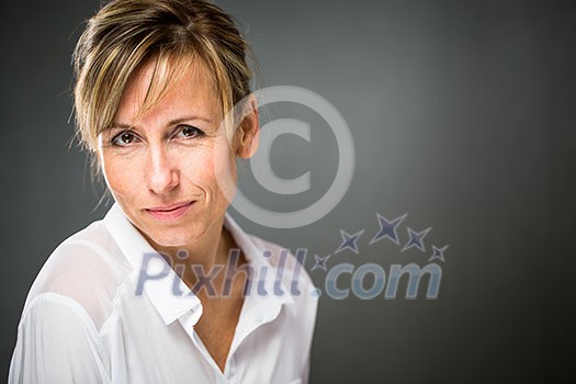 Portrait of a smiling middle aged caucasian woman against dark background - radiating confidence and feminity (shallow DOF; color toned image) Portrait of a smiling middle aged caucasian woman against dark background - radiating confidence and feminity (shallow DOF; color toned image)