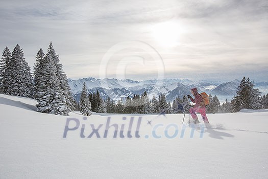 Pretty, young woman snowshoeing in high mountains, enjoying splendid winter weather with abundance of snow Pretty, young woman snowshoeing in high mountains, enjoying splendid winter weather with abundance of snow