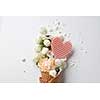 Beautiful flower in ice cream cone with meringues and waffle heart on a white background