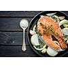 Raw salmon steak with herbs, onion, garlic and salt on a vintage pan on wooden rustic background. Top view. 