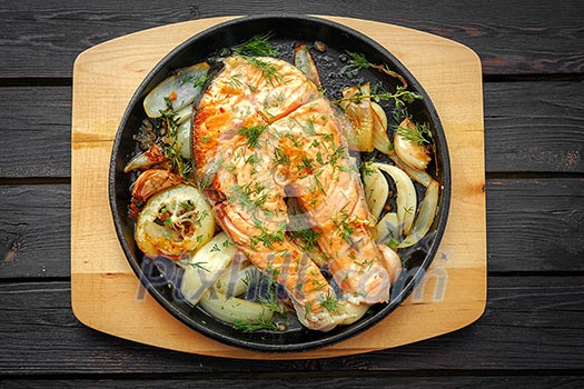 Frying pan with salmon steak, stir-fry veggies, lemon, onion and herbs Frying pan with salmon steak, stir-fry veggies, lemon, onion and herbs