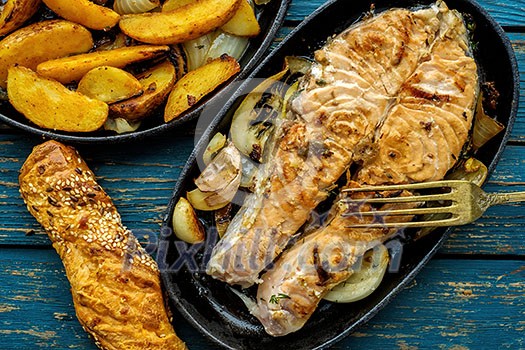 Frying pan with salmon steak, stir-fry veggies, lemon, onion, garlic and herbs Frying pan with salmon steak, stir-fry veggies, lemon, onion, garlic and herbs