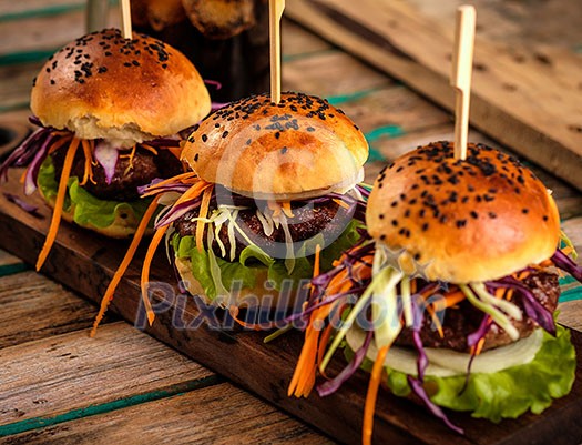 Three delicious fresh homemade burgers on a wooden table