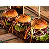 Three delicious fresh homemade burgers on a wooden table