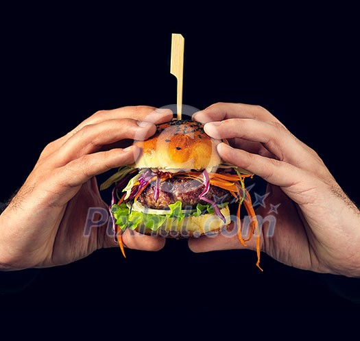 Hamburger burger with beef, carrot, cabbage and onion in man hands