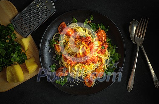 Top view of a plate of spaghetti with tomatoes.