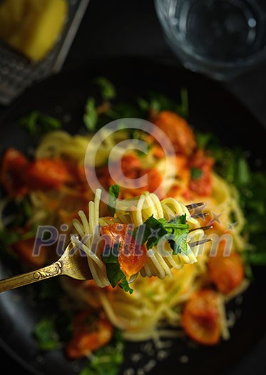 Spaghetti on a fork. Pasta with fresh tomatoes and herbs top view
