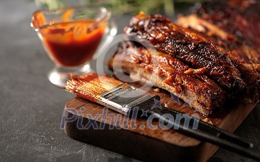 Delicious barbecued ribs seasoned with a spicy basting sauce and served with chopped fresh vegetables on an old rustic wooden chopping board in a country kitchen. Delicious barbecued ribs seasoned with a spicy basting sauce and served with chopped fresh vegetables on an old rustic wooden chopping board in a country kitchen.