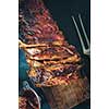 Delicious barbecued ribs seasoned with a spicy basting sauce on an old rustic wooden chopping board in a country kitchen. Top view. Retro toned.