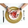 Beautiful female hands with jewelry at the table with a pomegranate on a plate.