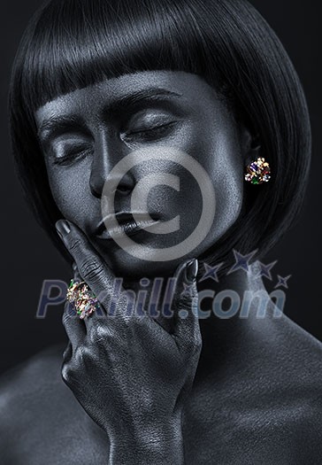 Fashion portrait of a dark-skinned beautiful girl with jewerly. Black Beauty face. Picture taken in the studio on a black background.