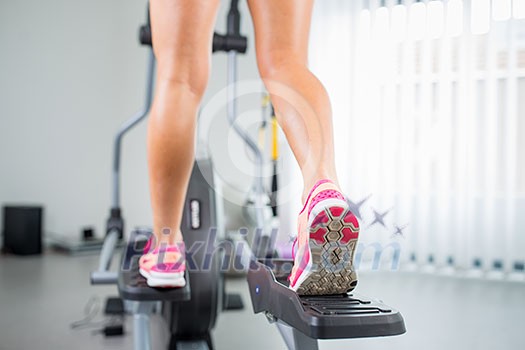 Young woman's muscular legs on stepper/treadmill, closeup