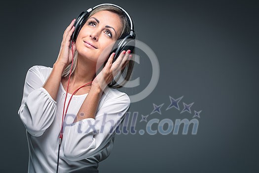 Pretty, young woman listening to her favorite music on hi-fi headphones, dancing, enjoying the tune, having a moment for herself Pretty, young woman listening to her favorite music on hi-fi headphones, dancing, enjoying the tune, having a moment for herself