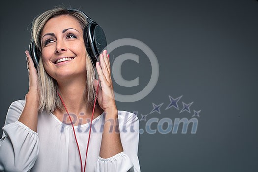 Pretty, young woman listening to her favorite music on hi-fi headphones, dancing, enjoying the tune, having a moment for herself Pretty, young woman listening to her favorite music on hi-fi headphones, dancing, enjoying the tune, having a moment for herself
