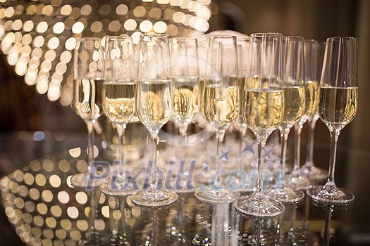Champagne flutes on shiny, glassy background with lovely blurred lights in the background