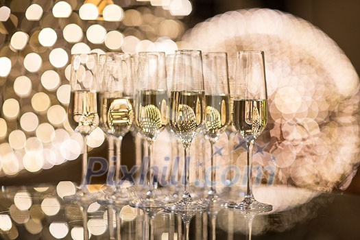 Champagne flutes on shiny, glassy background with lovely blurred lights in the background Champagne flutes on shiny, glassy background with lovely blurred lights in the background