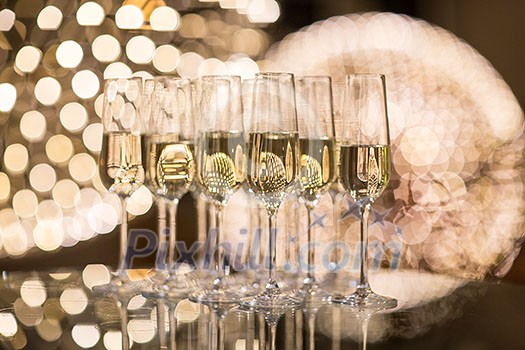 Champagne flutes on shiny, glassy background with lovely blurred lights in the background