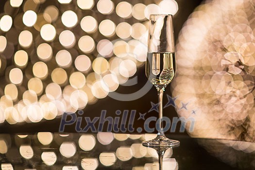 Champagne flutes on shiny, glassy background with lovely blurred lights in the background