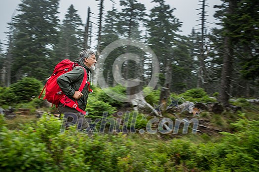 Active senior hiking in high mountains (motion blur technique used to convey movement of the hiker - he is tack sharp, the surroundings is blurred)