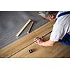 DIY, repair, building and home concept - close up of male hands lying parquet floor board/laminate flooring (shallow DOF; color toned image)