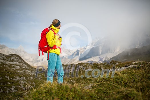 Pretty, young female hiker walking in high mountains (shallow DOF)