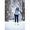 Young woman ice skating outdoors on a pond on a freezing winter day (color toned image; motion blurred image)