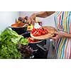 Young woman cutting vegetables in her modern kitchen - fixing a salad