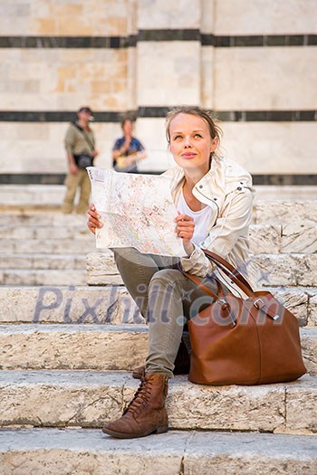 Gorgeous female tourist with a map discovering a foreign city (shallow DOF; color toned image)