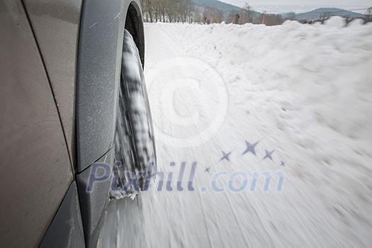 Car with winter tires on a slippery, snowy road - motion blur techinque used to convey movement, speed of the car