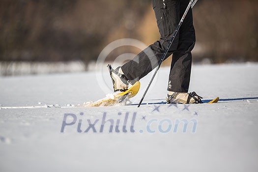 Young woman snow-shoeing - detail of the lengs in the snow