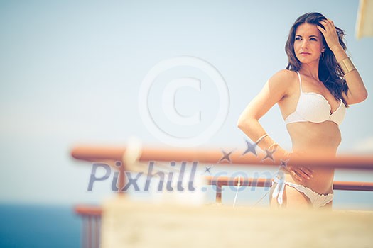 Beauty, spa and resort concept - beautiful, young woman by the sea on a balcony of a resort/hotel room Beauty, spa and resort concept - beautiful, young woman by the sea on a balcony of a resort/hotel room