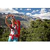 Pretty, young woman hiker taking a selfie photo with her smart phone in high mountains