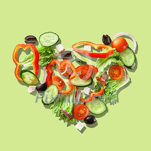 Heart from slices of vegetables isolated on a green background