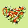 Heart from slices of vegetables isolated on a green background