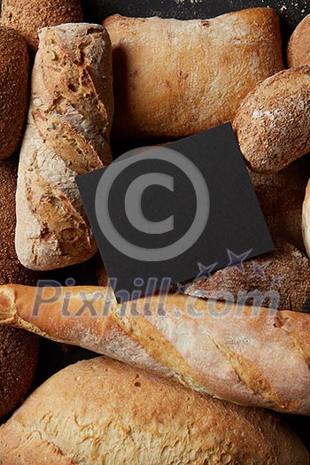 Baking and cooking concept background. Top view with copy space on black wooden table. Border of different bread sorts.