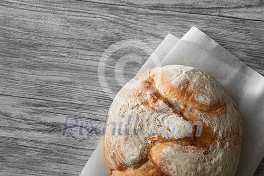 Homemade rye artisan sourdough bread over white wooden background. Top view of bread represented on cooking paper. Blank copy space for noting your ideas and emotions.