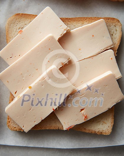 Sandwich with sliced cheese over white cooking paper. Sandwich for having snack or bread during your work. Sandwich with sliced cheese over white cooking paper. Sandwich for having snack or bread during your work.