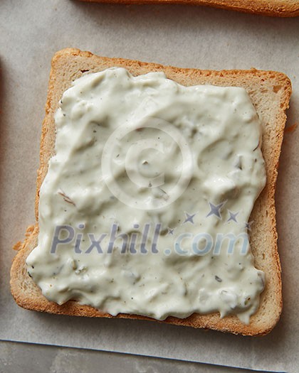 Sandwich with cream sauce over white cooking paper. Sandwich for having snack or bread during your work. Sandwich with cream sauce over white cooking paper. Sandwich for having snack or bread during your work.