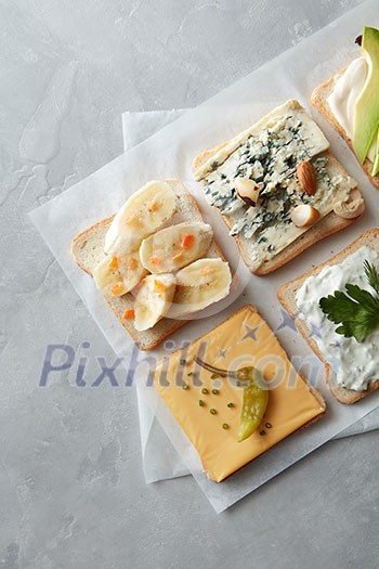 Top view of different kinds of colorful sandwiches on white chalkboard background. Party starter or appetizer - flat lay composition. Top view of different kinds of colorful sandwiches on white chalkboard background. Party starter or appetizer - flat lay composition.