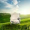 Arm chair represented on green grass with landscape on sunset. Beautiful dawn in spring or summer time. Landscape concept.