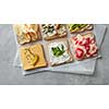 Different kinds of colorful sandwiches on white chalkboard background from above (top view). Party starter or appetizer - flat lay composition.