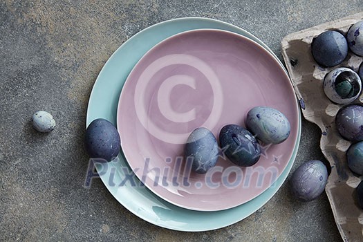 two plates with dyed eggs and a paper tray on a stone table