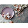 pink plate with eggs and paper tray with dried petals on a concrete background